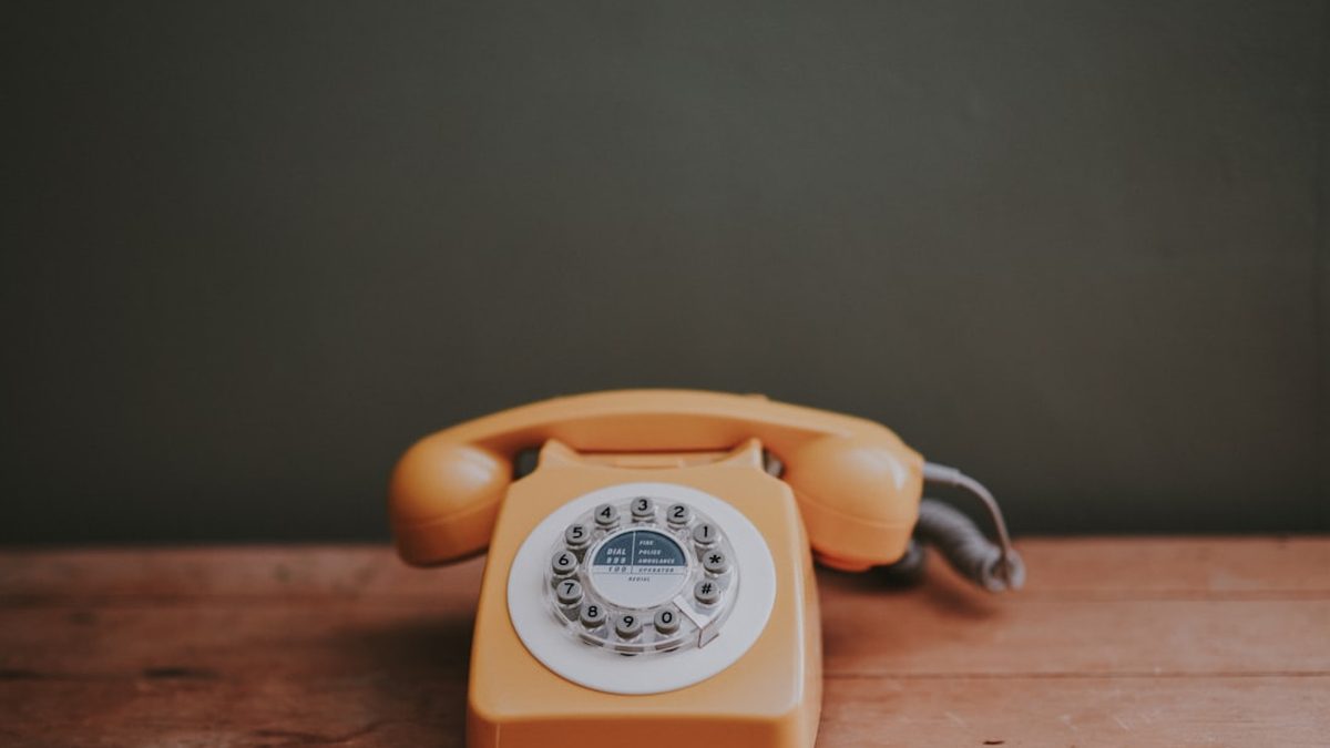 brown rotary dial telephone in gray painted room