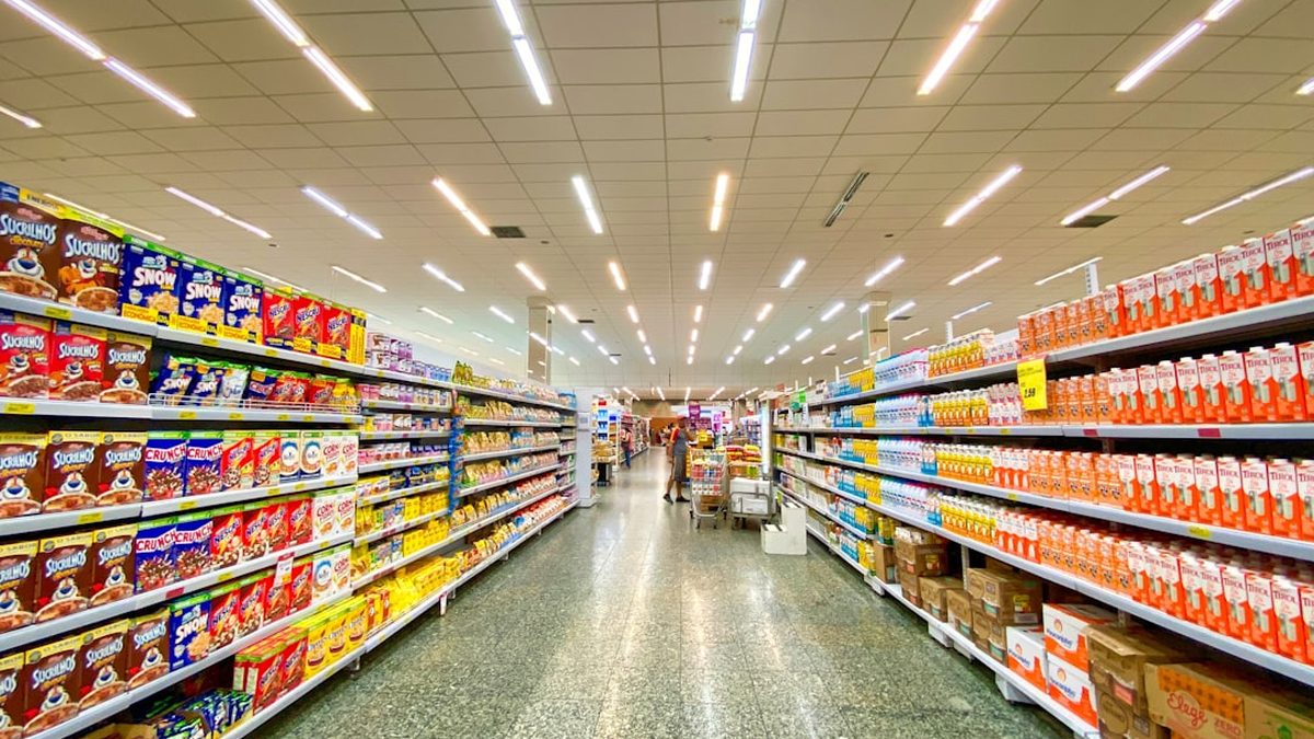 A grocery store aisle with shelves stocked with cereal boxes and milk cartons
